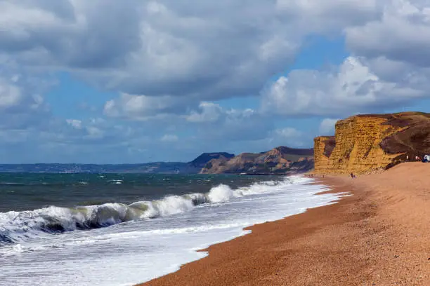 Freshwater Bay beach and waves Dorset view towards sandstone cliffs, West Bay and Golden Cap