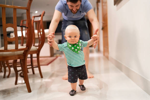 istock Father helping son learn to walk at home 1173589768