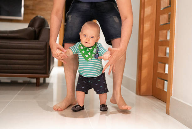 istock Father helping son learn to walk at home 1173589819