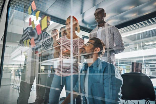 istock Diverse businesspeople brainstorming with sticky notes on a glass wall 1173590046