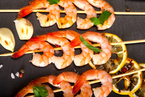 istock Prawns Shrimps with lemon, garlic and herbs on black background. Top view 1173593524