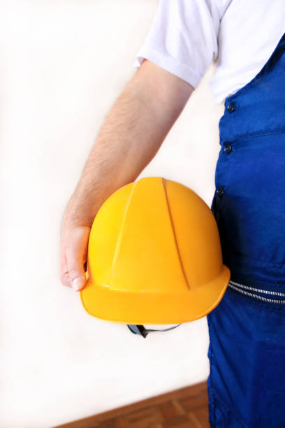 istock Construction worker and handyman is working on renovation of apartment. Builder at construction site with protective uniform and equipment, he with suit, coverall and yellow helmet holding in hand. 1173594611