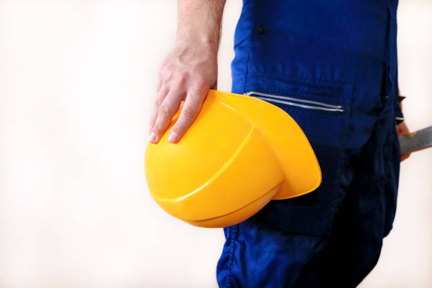 istock Construction worker and handyman is working on renovation of apartment. Builder at construction site with protective uniform and equipment, he with suit, coverall and yellow helmet holding in hand. 1173594757
