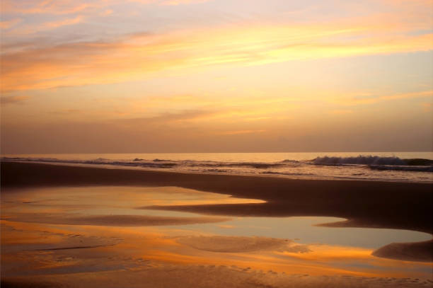 Marine background with beautiful colorful sky reflects in a shallow water during low tide before sunrise. Scenic seascape at the Pawleys Island, South Carolina, USA.