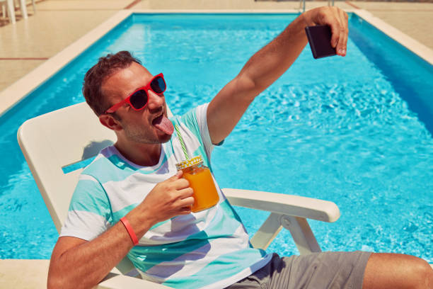 istock Attractive man using cellphone while drinking juice near swimming pool. 1173595158