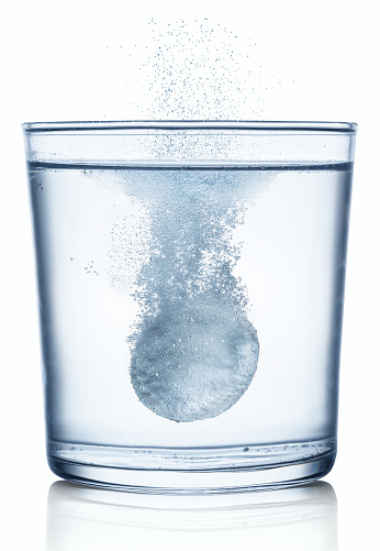 Comprimido efervescente disolviéndose en un vaso de agua. Aislado sobre fondo blanco. photo
