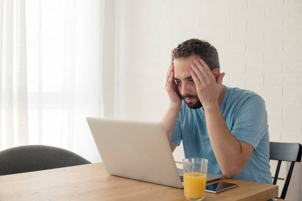 istock Young man disappointed while working on laptop. He is sitting at table at home. 1173596612