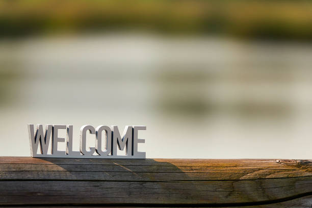 signe de bienvenue sur le fond extérieur au coucher du soleil - text wood alphabet nature photos et images de collection