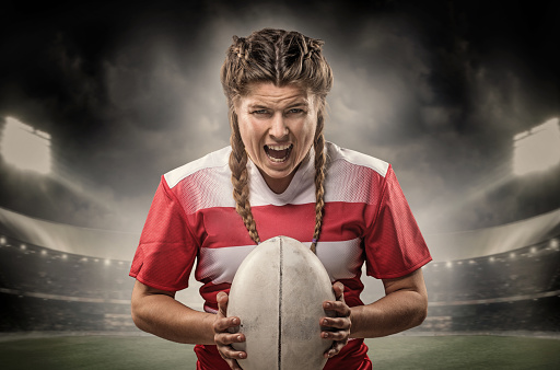 Cropped image of sports player holding ball against rugby stadium