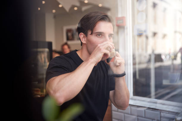 istock Young Man In Coffee Shop Talking On Mobile Phone Viewed Through Window 1173599946