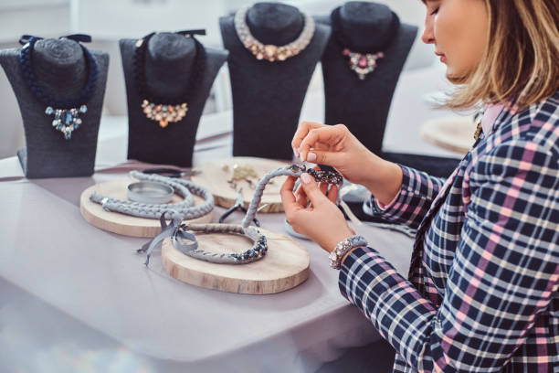 istock Elegantly dressed woman makes handmade necklaces, working with needles and thread in workshop. 1173602439