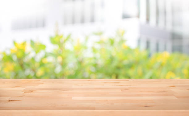 istock Real wood table top texture on blur leaf tree garden and wall building from city,park 1173603643