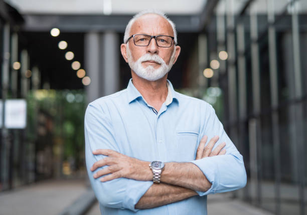 istock Senior entrepreneur standing outdoors next to office buildings and looking at camera. 1173604334