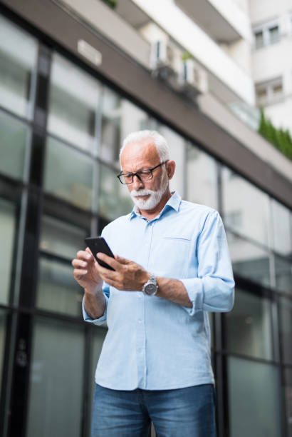 istock Serious senior businessman using phone outdoors. 1173604367