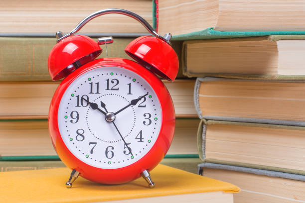 istock Red alarm clock among books and textbooks, educational concept, back to school 1173604880