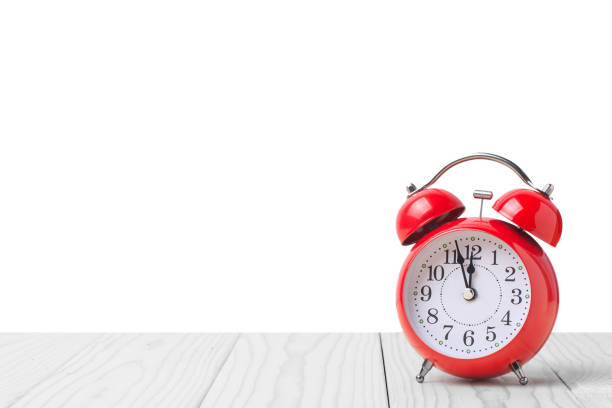 istock Red alarm clock on light wooden table isolated on white background 1173605317