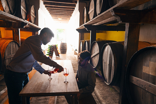 Winemakers wine tasting in oak barrels winery cellar