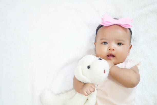 신생아 아기 소녀 포옹과 흰색 배경에 그녀의 개 인형을 껴안고 - baby doll dress 뉴스 사진 이미지