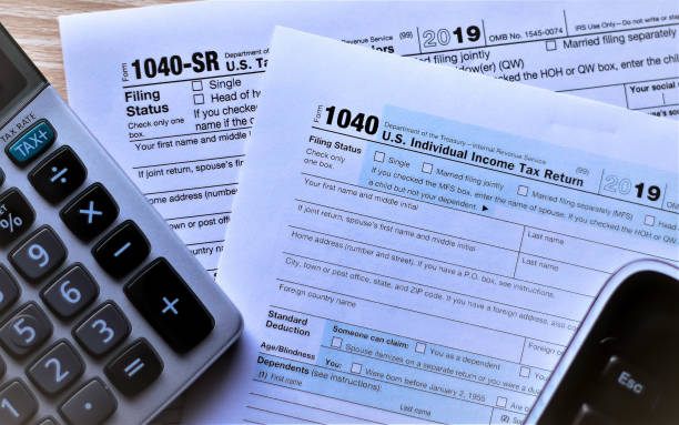US Income tax forms 1040 and new 1040 SR for 2019 Forms 1040 and new Form 1040 SR for seniors on desktop with escape key showing from keyboard and tax key on calculator. Concept is escaping from deciding which form to use. 1040 tax form photos stock pictures, royalty-free photos & images