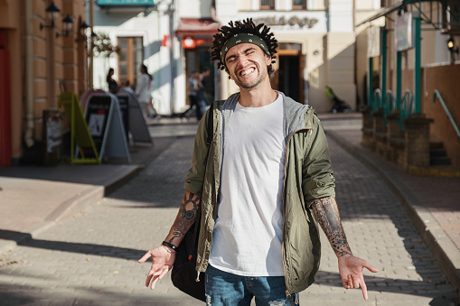 Handsome young man with dreadlocks hairstyle and head scarf, gangsta rap singer, rapper in city street. Afroamerican underground style. Close up portrait of man dressed autumn fashion stylish outfit