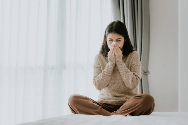 istock Sick Asian woman using a tissue to sneeze 1173615659