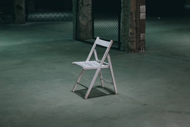 istock An empty chair in a dark room. A lonely object standing in empty concrete walls at dusk, a symbolism of loneliness of fear, mysticism, torture 1173618143