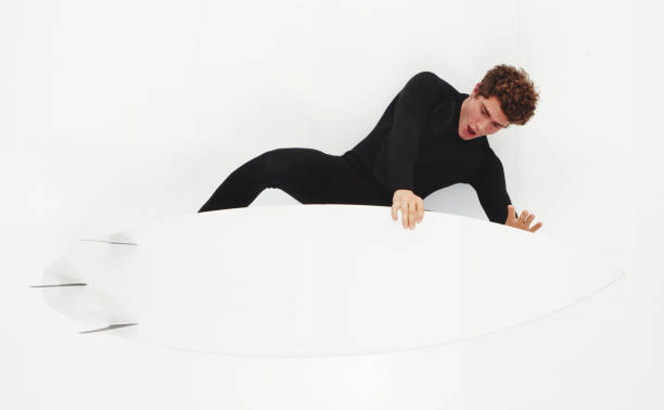 One man only / full length / directly above view of 20-29 years old adult handsome people caucasian male / young men lying down in front of white background wearing wetsuit / swimwear who is excited / happy / smiling / successful / shouting and celebration who is barefoot and using surfboard / surfing / sport / surf / thank you - phrase un hombre solamente / longitud completa / directamente por encima de la vista de 20-29 años de edad adulto guapo personas caucásicas hombres / jóvenes acostados frente a fondo blanco usando traje de neopreno / traje de baño que está emocionado / feliz