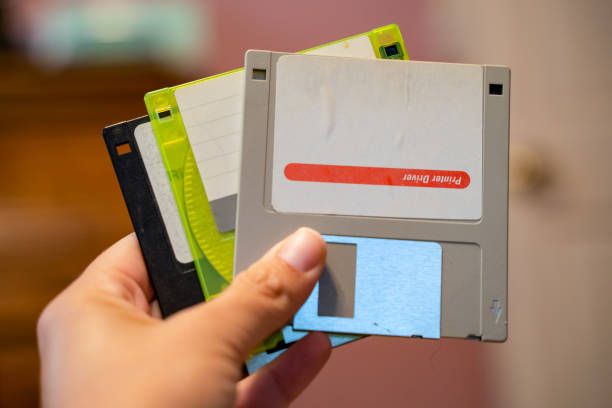 istock Hand holds out Three outdated 3.5 inch floppy disks, from the 1990s 1173619856