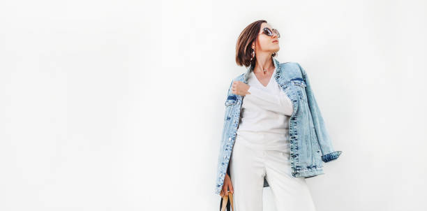 femme de pose dans la tenue blanche élégante avec la veste en denim surdimensionnée - women spring sensuality fashion model photos et images de collection