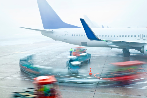 Baggage handling in fog. Long exposed image with motion blur