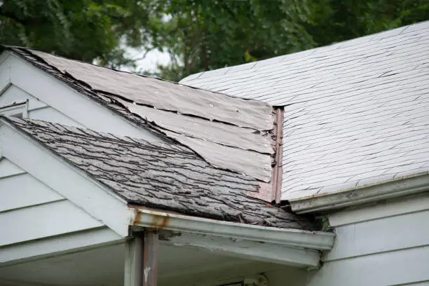 Photo of Damaged and old roofing shingles and gutter system on a house