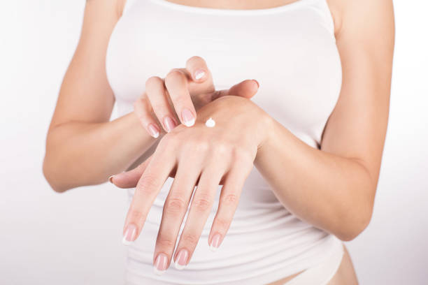 istock Female hands with classic manicure applying cream, white background, close up 1173632765