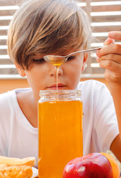 Child grabs honey from the jar with the spoon