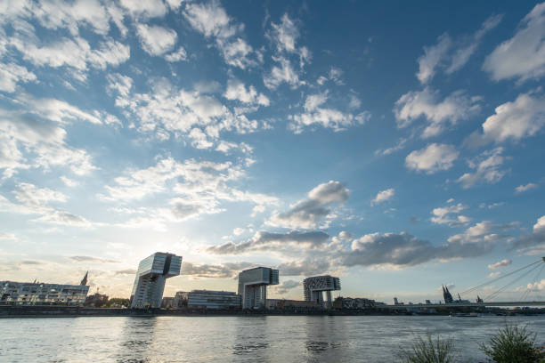 panoramic skyline view of the rhine shore in cologne with river in the foreground and crane houses with cathedral in the back on a sunny afternoon in september