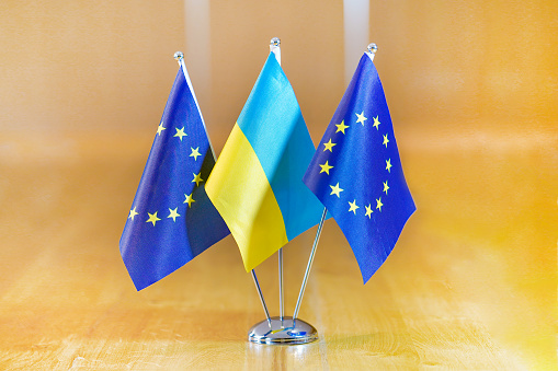 Three flags on the table. Flags of Ukraine, European Union. Flags of European Union and Ukraine on the table during a meeting of foreign ministers of European Union and Ukraine.