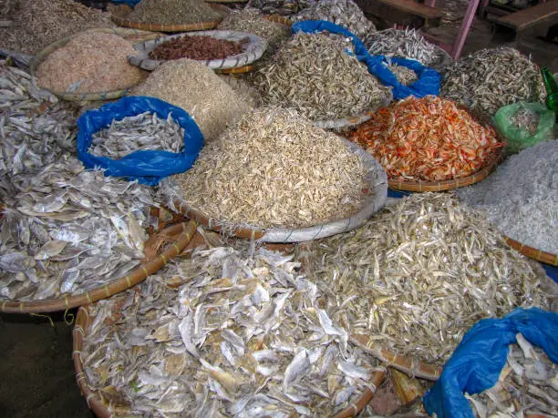 Wicker trays filled with different kinds of small dried fish, earning money by selling food on an asian market