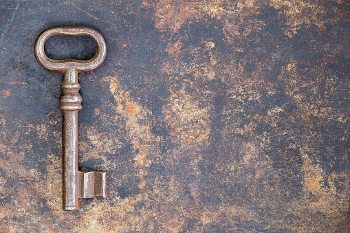 Antique rusty ornate key on grunge metal background, escape room concept