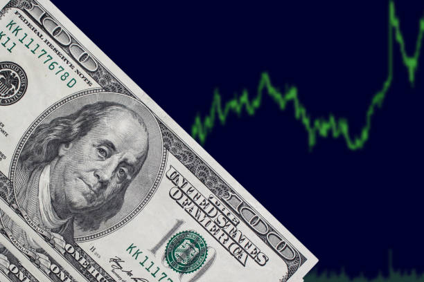 istock One hundred dollar bills on a blue background with a trading chart. American dollars on a blue background. 1173647011