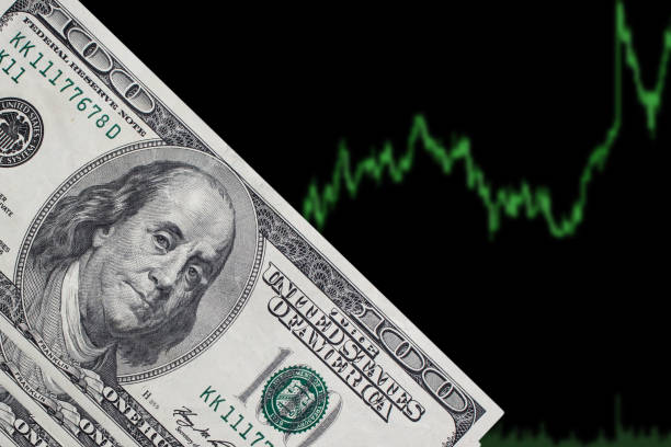 istock One hundred dollar bills on a black background with a trading chart. American dollars on a blue background. 1173647022