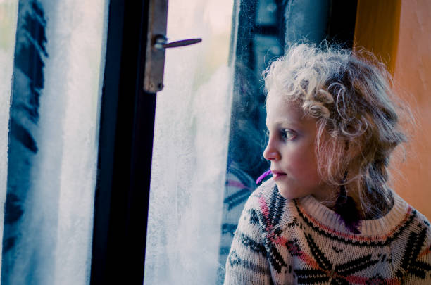 istock sad girl by window 1173651233