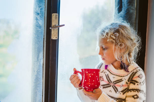 istock lovely child drinking tea by the window 1173654670