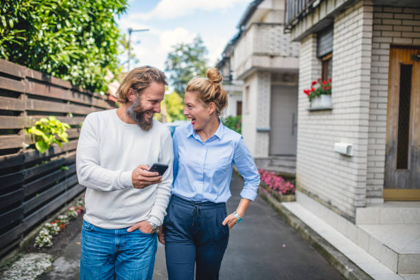 Heterosexual Caucasian Couple Using Smart Phone and Walking Down the Street