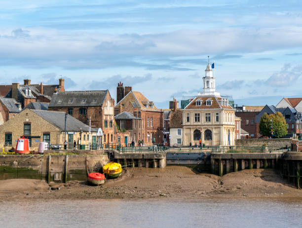 King's Lynn's former Custom House and entrance to the Purfleet A view from West Lynn across the River Great Ouse to the old former Hanseatic port of King’s Lynn in Norfolk, Eastern England. Right of centre is the old former Custom House, built in the 17th century and one of the most famous buildings in the area, which has featured in a number of films and period dramas. The silted-up entrance to the Purfleet, once a busy tidal dock, is visible. (Incidental people.) kings lynn stock pictures, royalty-free photos & images