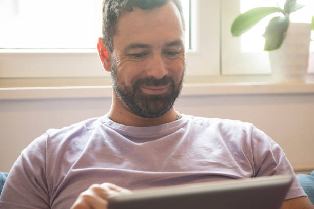 istock Mid adult man using digital tablet in living room 1173660156