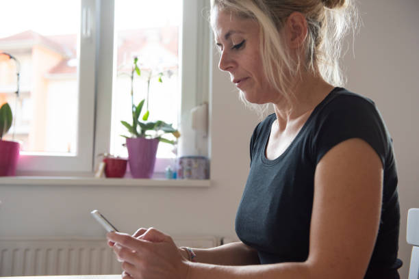 istock Mid adult woman using smart phone in kitchen 1173660228