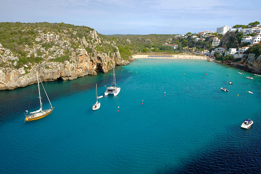 View on on the beach Cala en Porter and white boats on Menorca, Balearc Islans, Spain.