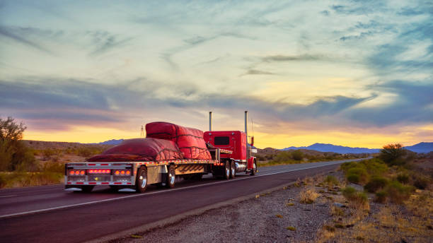 Long Haul Semi Truck On a Rural Western USA Interstate Highway Large semi truck hauling freight on the open highway in the western USA under an evening sky. trailer stock pictures, royalty-free photos & images