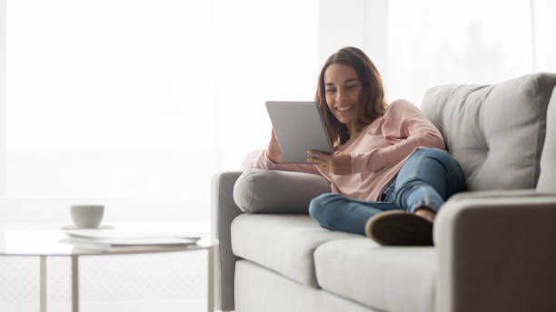 istock Smiling girl relax on couch watching video on tablet 1173666045