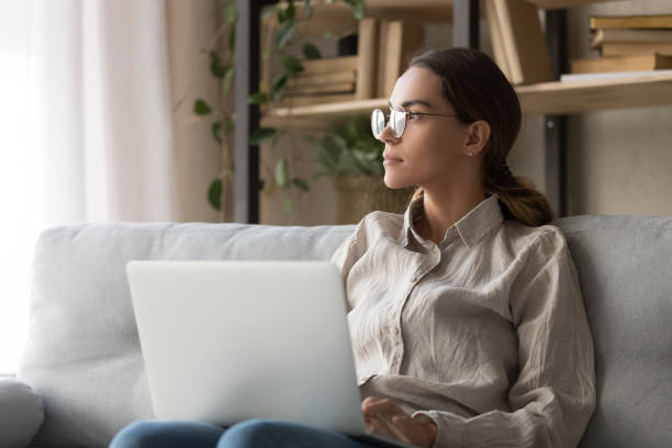 istock Dreamy female look in distance distracted from computer work 1173666138