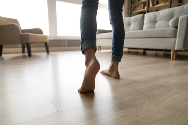 Close up of woman walking barefoot on warm wooden floor Close up of barefoot young woman in jeans feel comfortable walking on warm heated wooden floor at home, female step in her bare feet relaxing enjoy free sunny day in own modern apartment Barefoot stock pictures, royalty-free photos & images